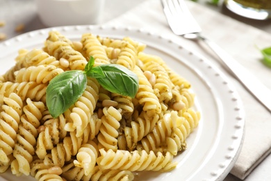 Plate with delicious basil pesto pasta on table, closeup