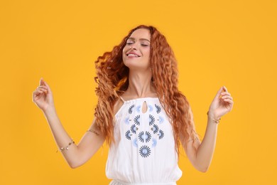 Photo of Beautiful young hippie woman dancing on orange background