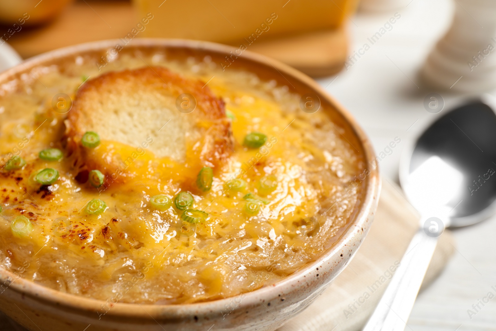 Photo of Tasty homemade french onion soup served in ceramic bowl, closeup