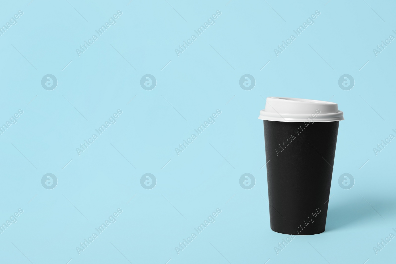 Photo of Takeaway paper coffee cup on light blue background. Space for text