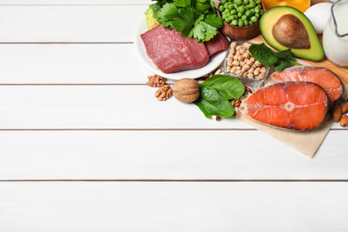 Different products rich in protein on white wooden table. Space for text