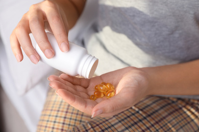 African-American woman with bottle of vitamin capsules at home, closeup