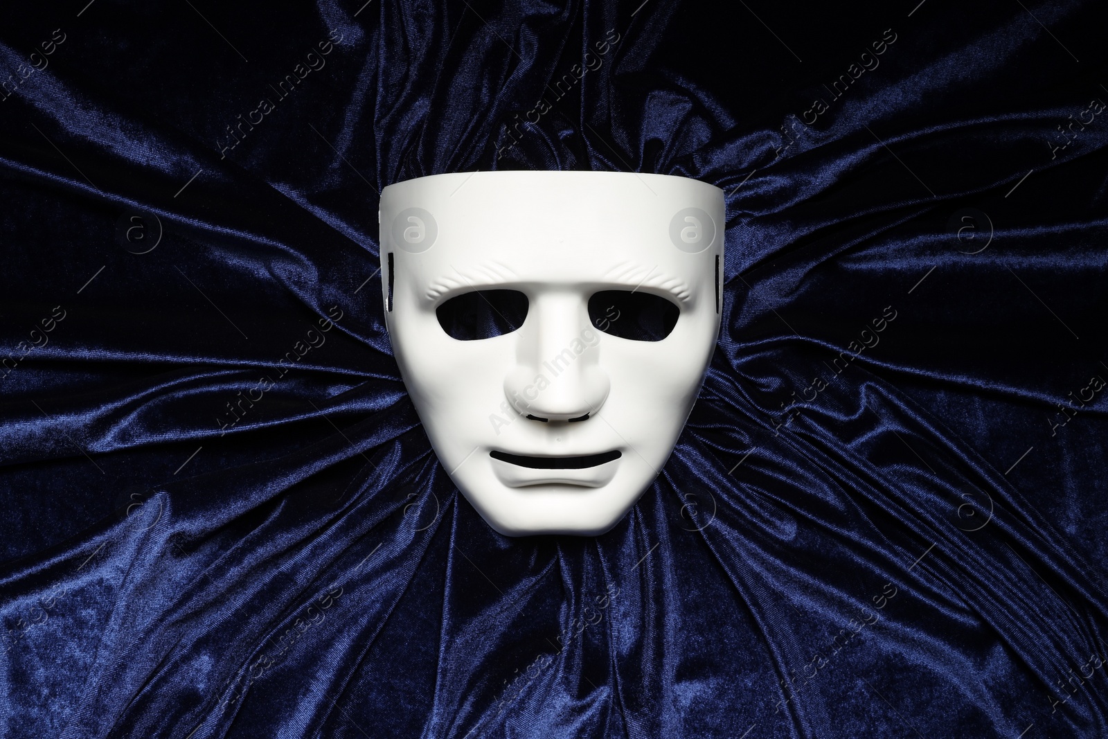 Photo of Theater arts. White mask on blue fabric, top view