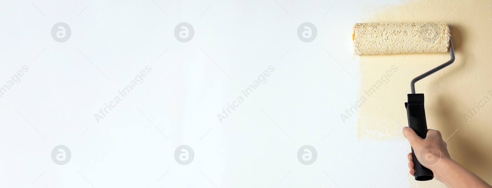 Image of Professional decorator painting white wall with beige dye, space for text. Banner design