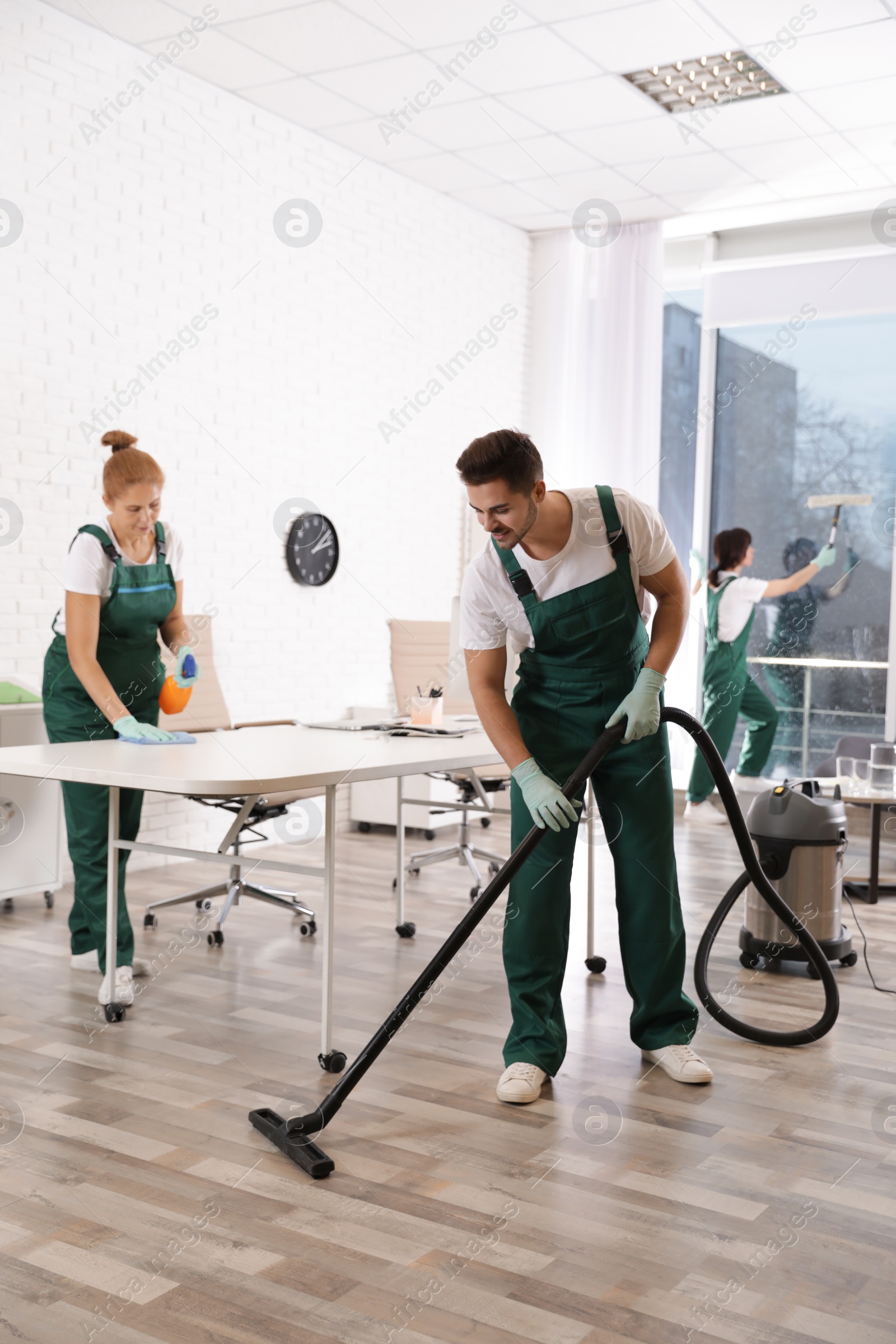 Photo of Team of professional janitors working in modern office. Cleaning service