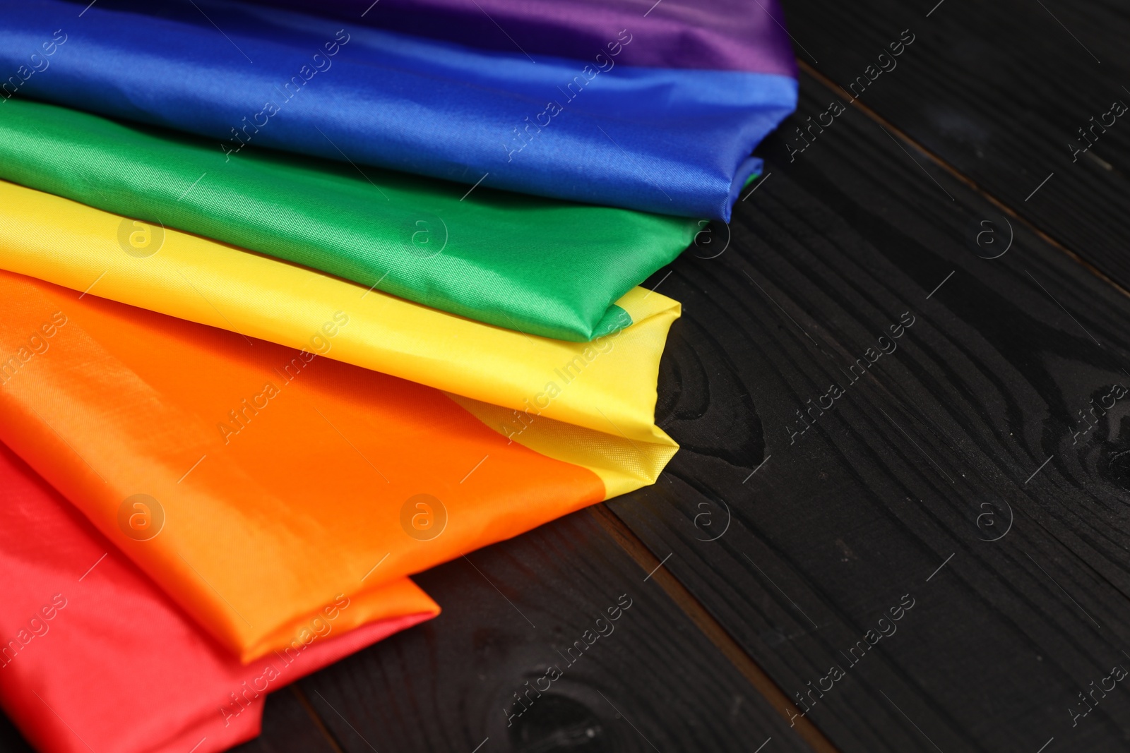 Photo of Rainbow LGBT flag on black wooden background, closeup