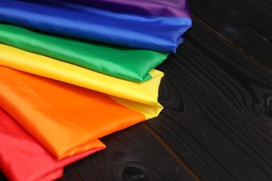 Photo of Rainbow LGBT flag on black wooden background, closeup