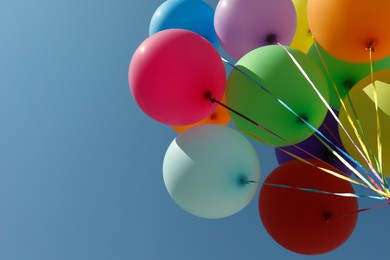 Photo of Bunch of colorful balloons against blue sky, bottom view. Space for text