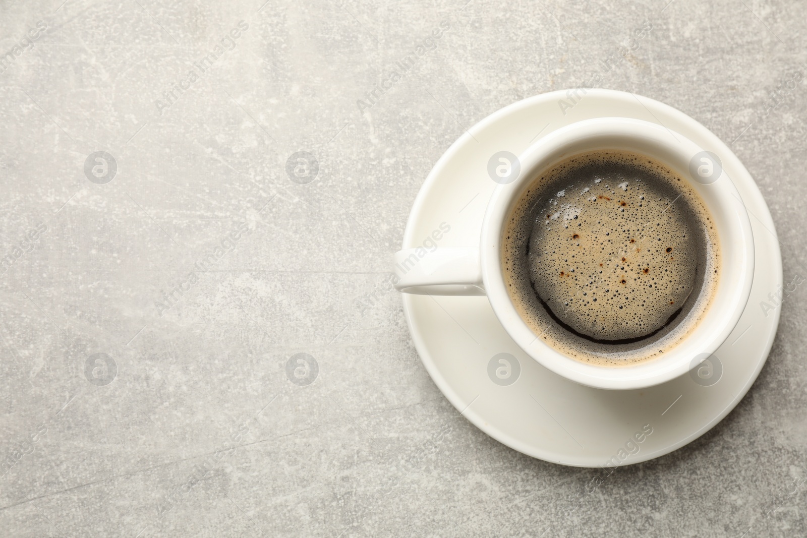 Photo of Cup of aromatic coffee on light grey table, top view. Space for text