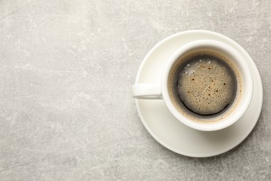 Cup of aromatic coffee on light grey table, top view. Space for text