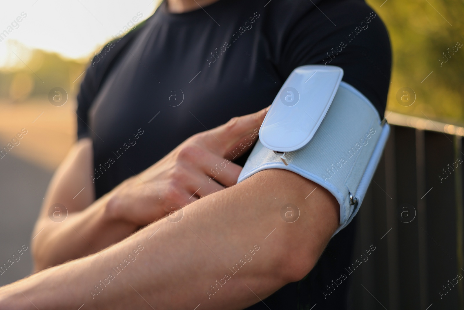 Photo of Man checking blood pressure with modern monitor outdoors, closeup