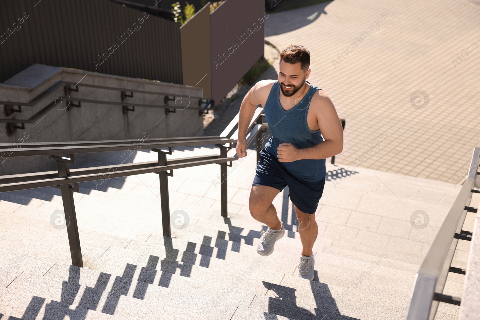 Photo of Smiling man running up stairs outdoors on sunny day. Space for text