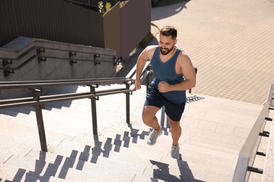 Photo of Smiling man running up stairs outdoors on sunny day. Space for text