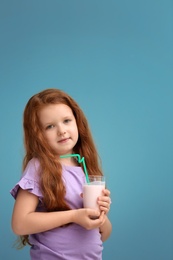 Little girl with glass of delicious milk shake on color background