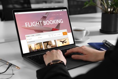 Image of Woman using laptop to book flight at white table, closeup