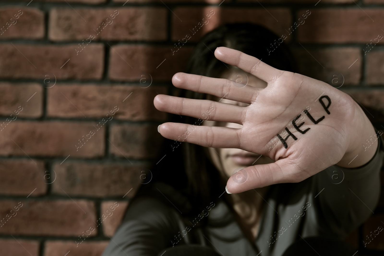 Photo of Domestic violence concept. Woman hiding her face, focus on hand with written word Help