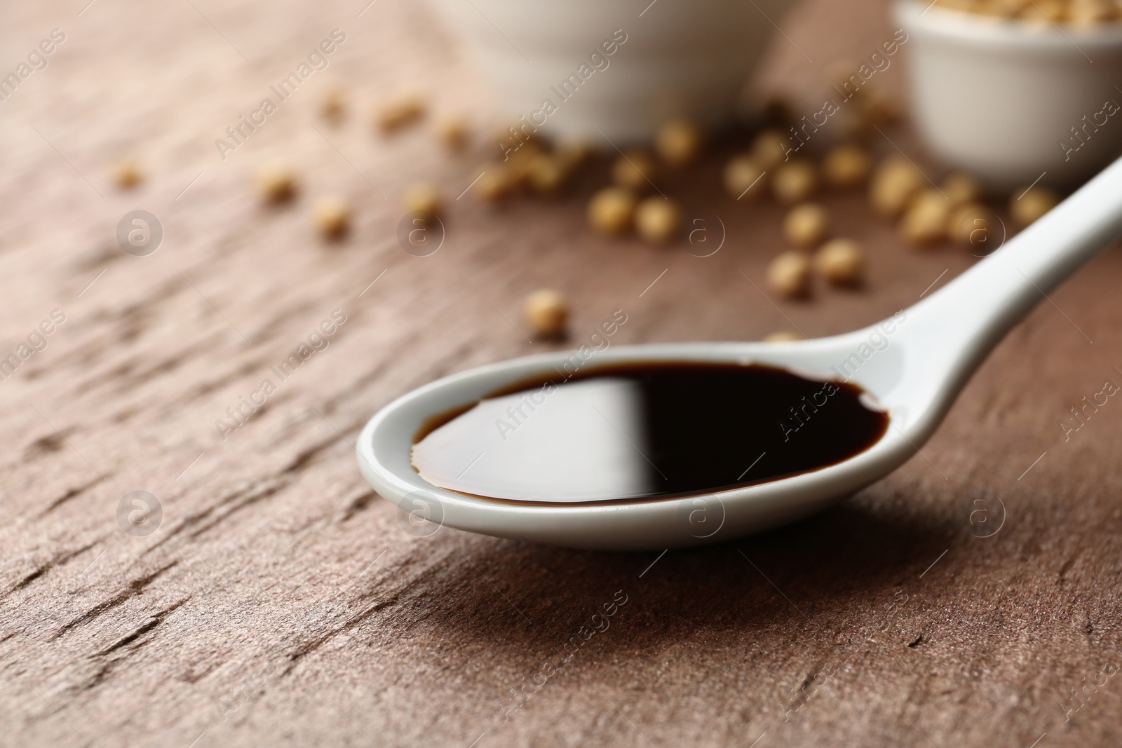 Photo of Spoon of soy sauce on table. Space for text