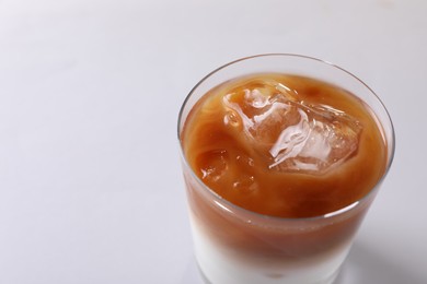 Photo of Glass of iced coffee on white table, closeup. Space for text