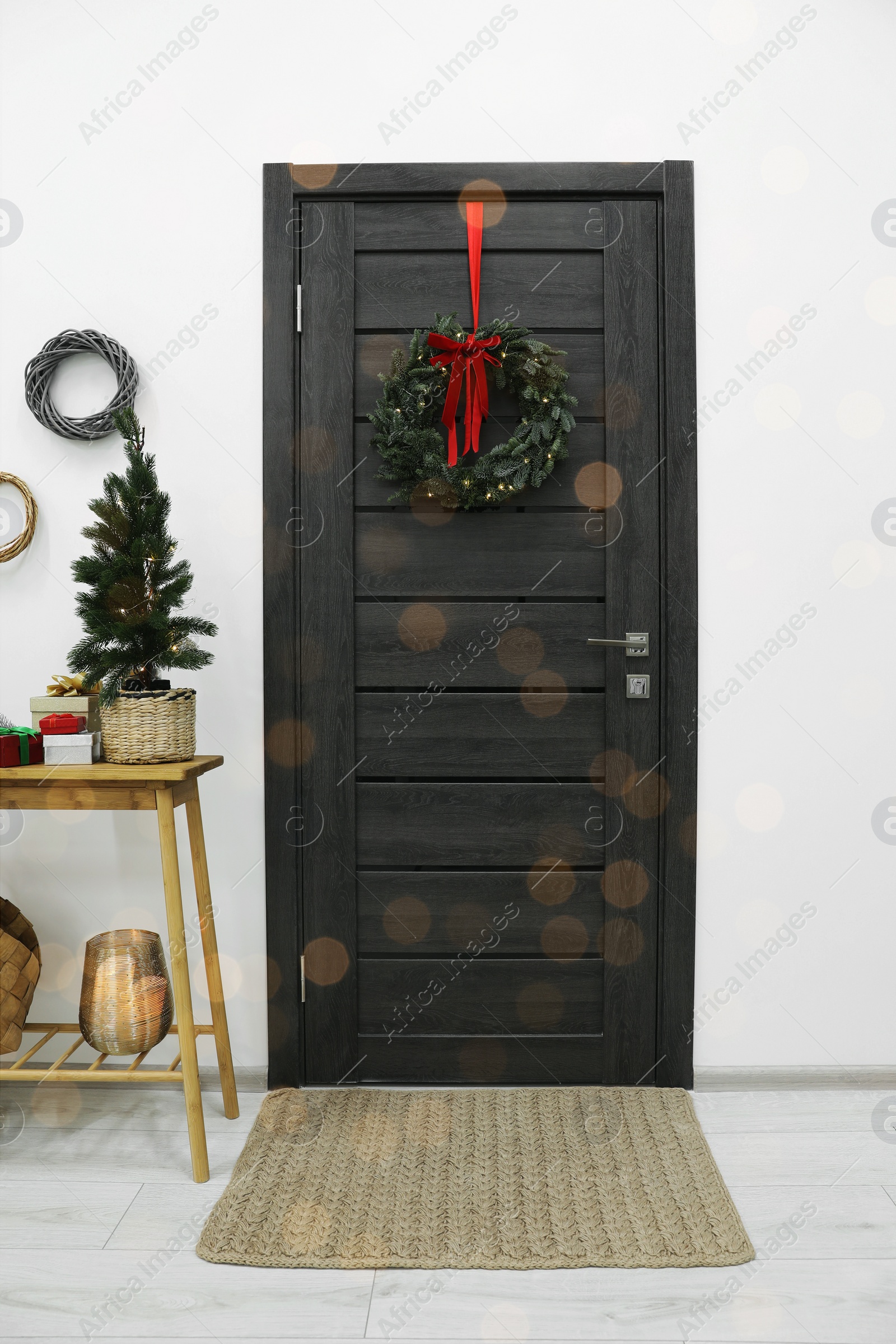 Photo of Beautiful Christmas wreath with red bow hanging on door and different festive decor indoors