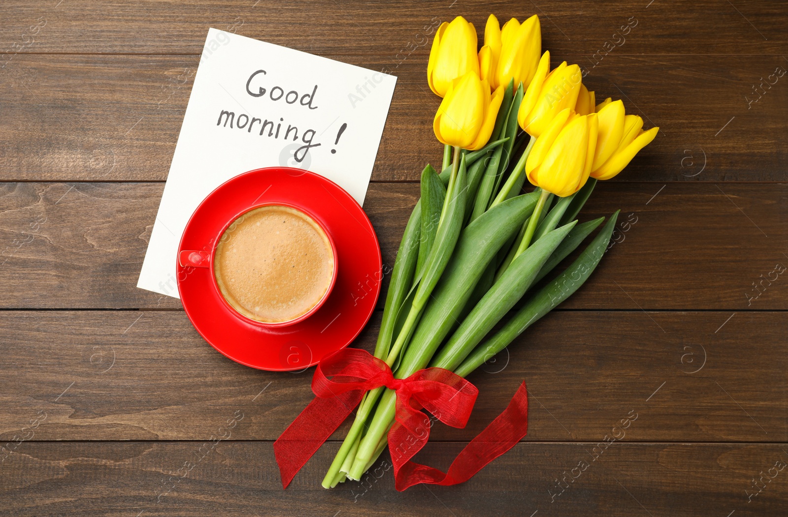 Photo of Beautiful yellow tulips, cup of aromatic coffee and Good Morning note on wooden table, flat lay