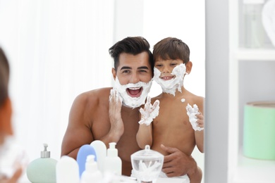 Photo of Father and son having fun while applying shaving foam in bathroom