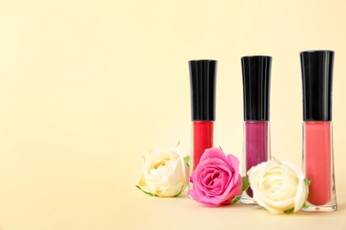 Lip glosses and flowers on color background