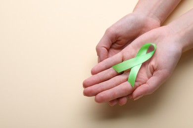 Photo of World Mental Health Day. Woman holding green ribbon on color background, closeup view with space for text