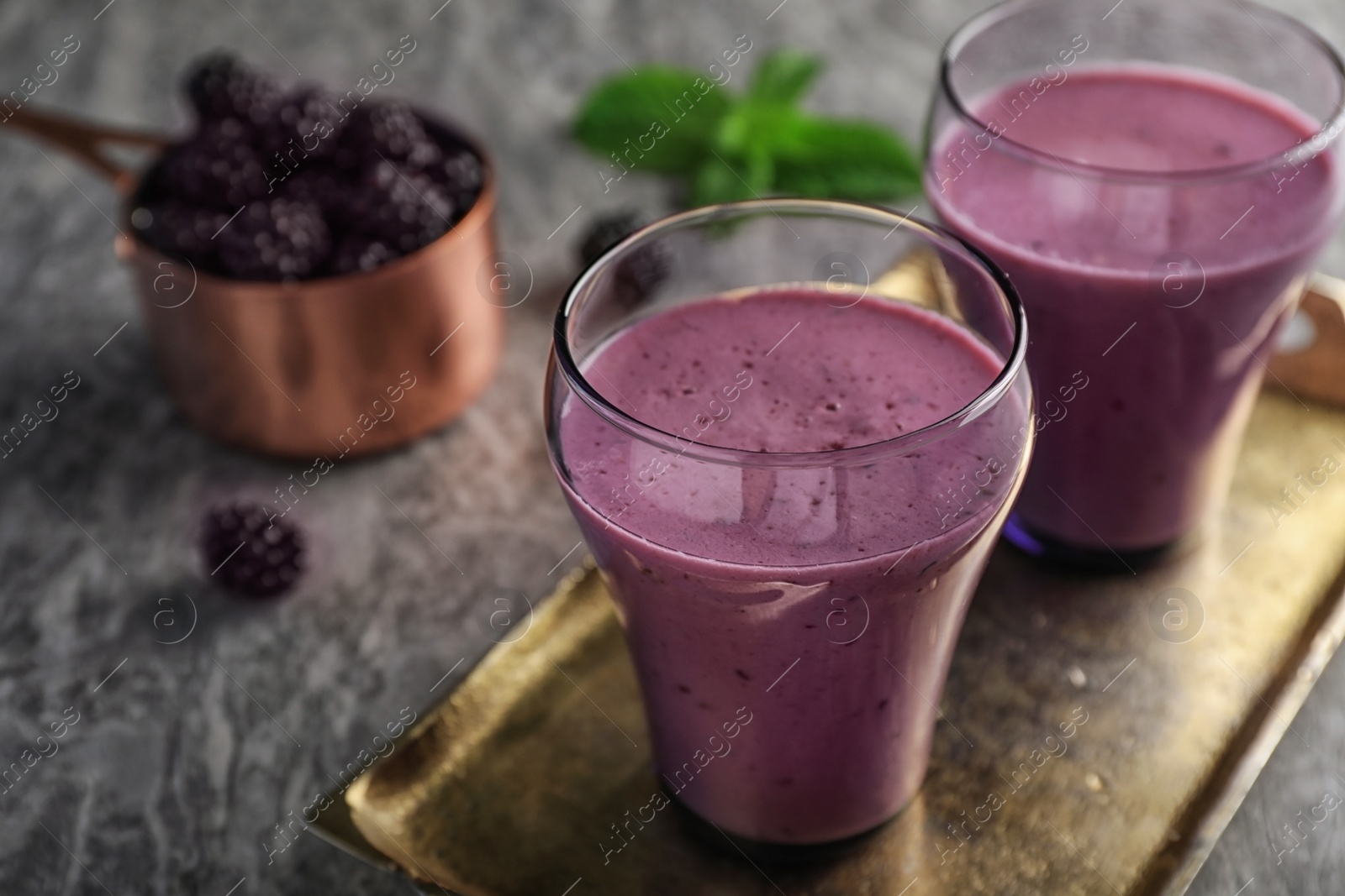 Photo of Glasses with tasty blackberry yogurt smoothies on grey table