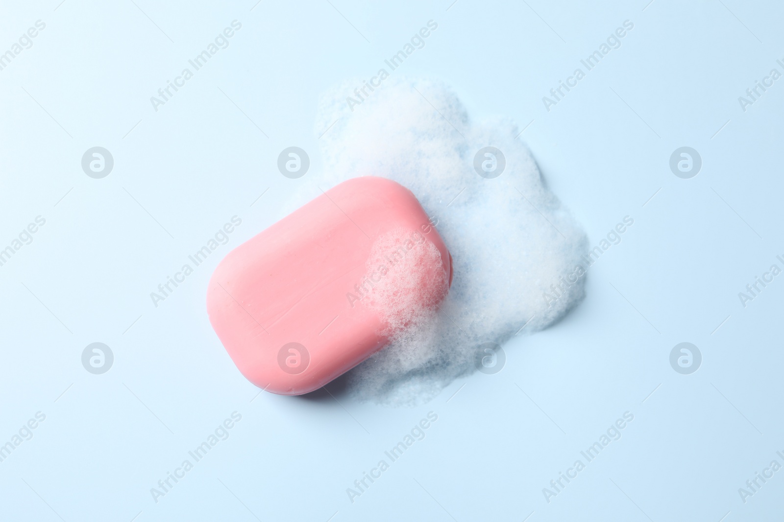 Photo of Soap with fluffy foam on light blue background, top view