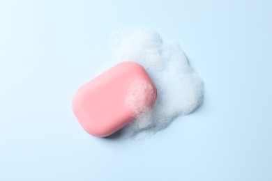 Photo of Soap with fluffy foam on light blue background, top view