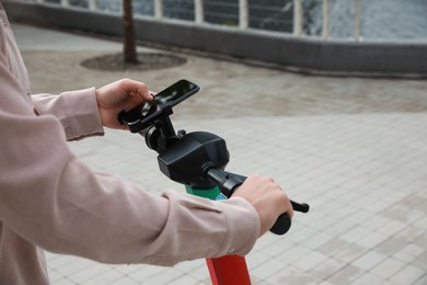 Photo of Man using smartphone to pay and unblock electric kick scooter outdoors, closeup. Space for text