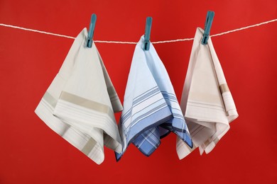 Photo of Many different handkerchiefs hanging on rope against red background