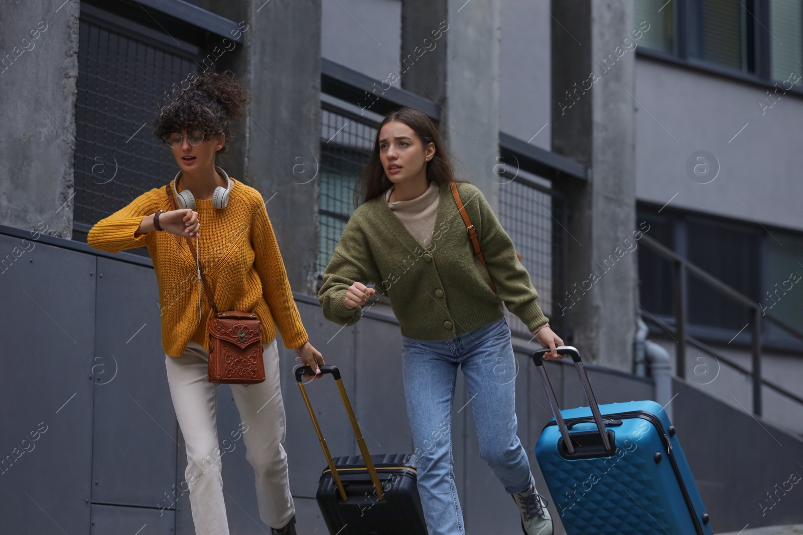 Photo of Being late. Worried women with suitcases running outdoors