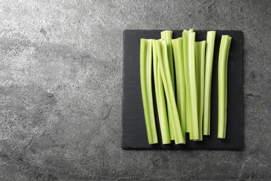 Photo of Board with fresh green cut celery on grey table, top view. Space for text