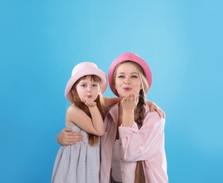 Happy woman and daughter in stylish clothes on color background