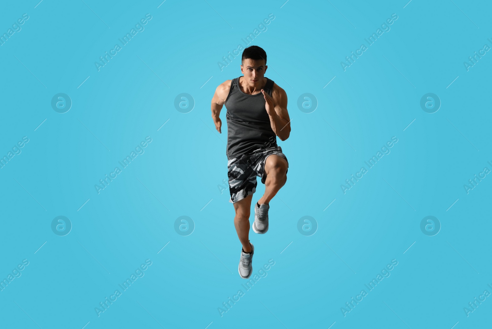 Photo of Athletic young man running on light blue background