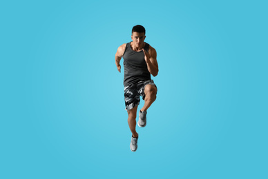 Photo of Athletic young man running on light blue background