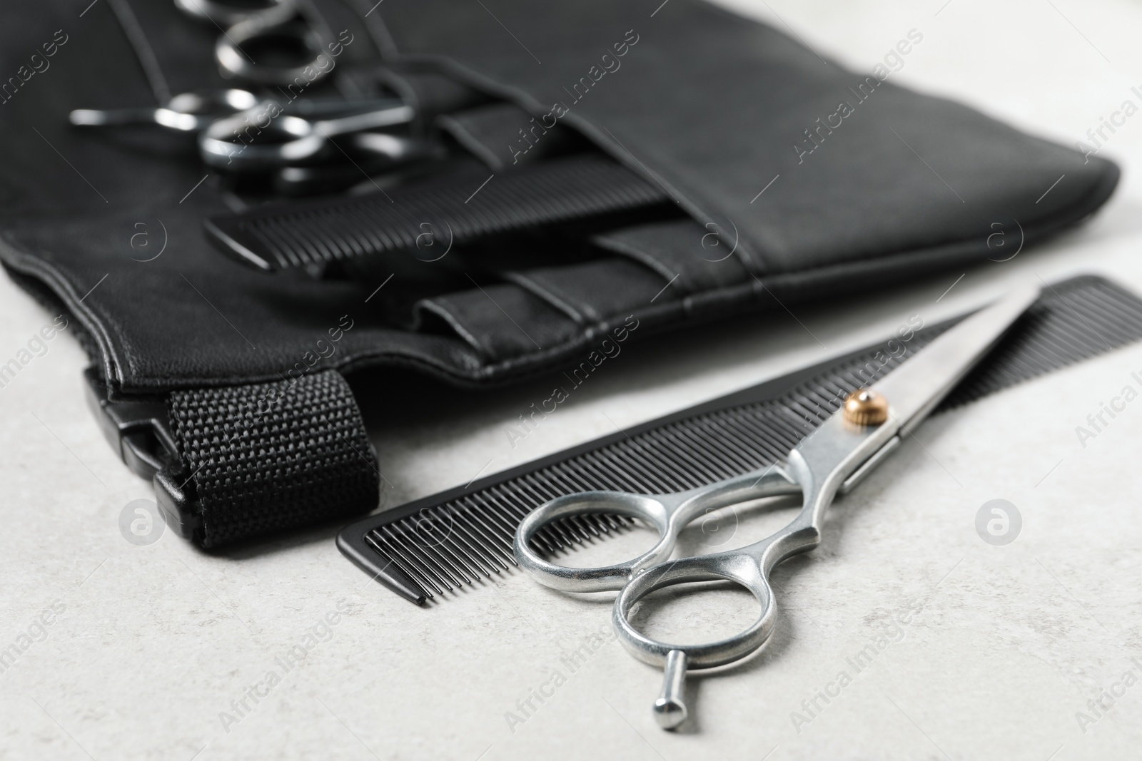 Photo of Hairdresser tools. Professional scissors, combs and leather organizer on white table, closeup