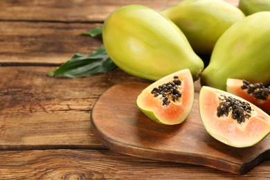 Photo of Fresh ripe papaya fruits on wooden table. Space for text