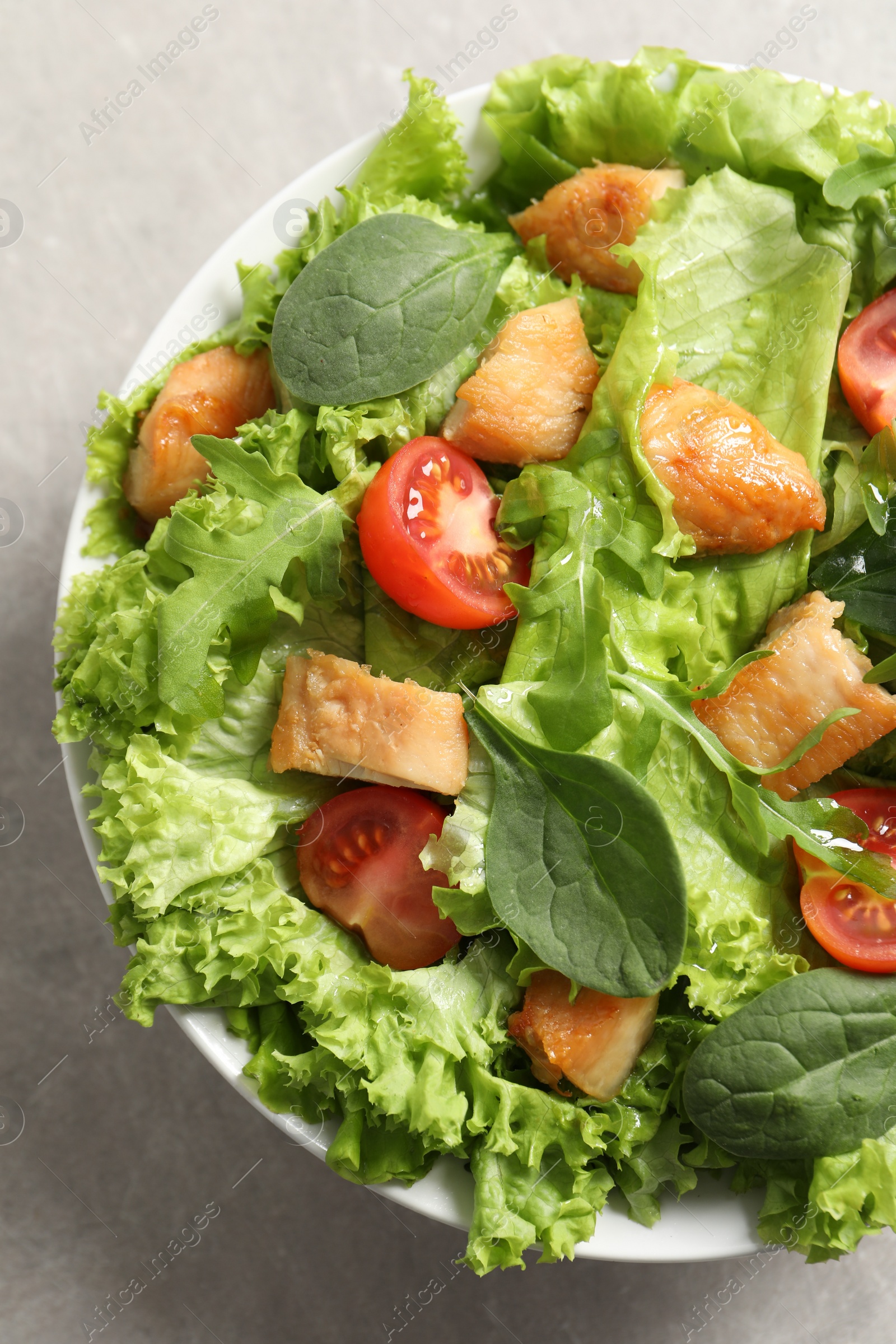 Photo of Delicious salad with chicken, cherry tomato and spinach on light grey table, top view
