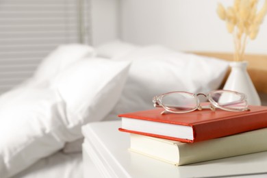 Photo of Books and glasses on white wooden bedside table in bedroom, space for text