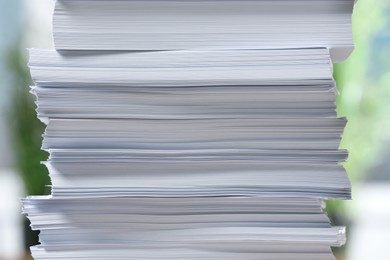 Photo of Stack of paper sheets against blurred background, closeup