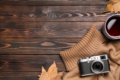Photo of Flat lay composition with cup of hot tea and autumn leaves on wooden background. Space for text