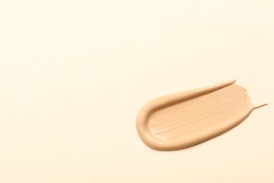 Photo of Smear of skin foundation on beige background, top view. Space for text