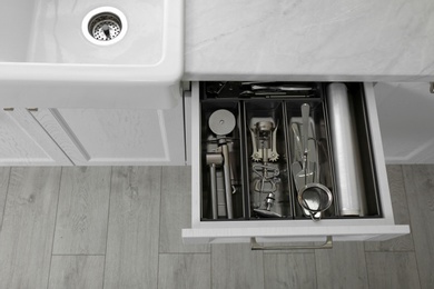 Open drawer with different utensils in kitchen, above view. Space for text
