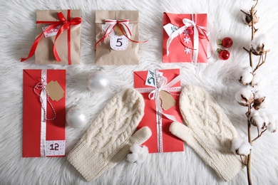 Flat lay composition with Christmas gifts, mittens and festive decor on white fluffy rug. Creating Advent calendar