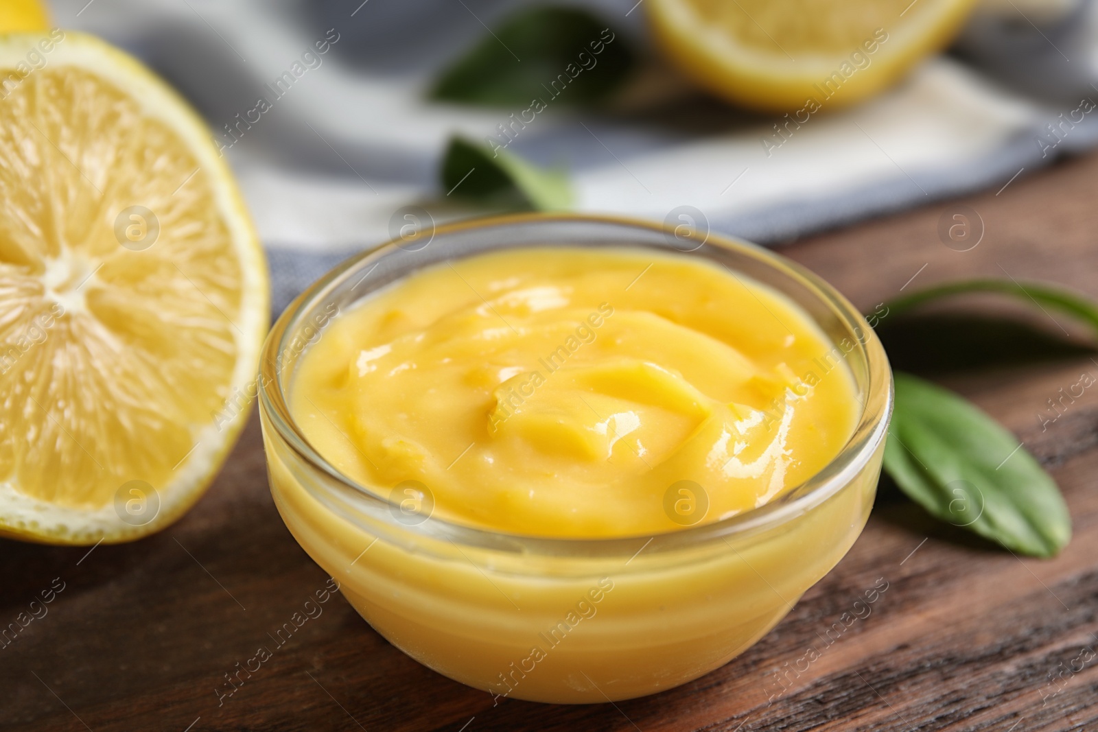 Photo of Delicious lemon curd in bowl on wooden table, closeup