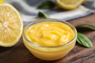 Delicious lemon curd in bowl on wooden table, closeup