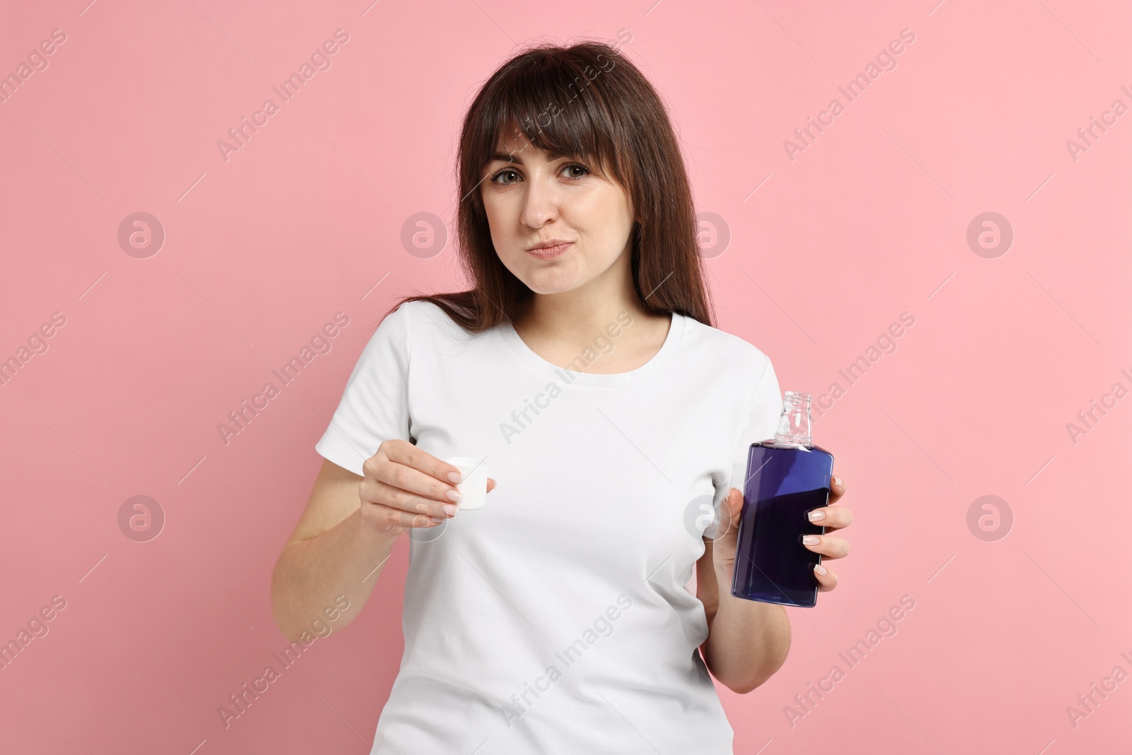 Photo of Young woman using mouthwash on pink background