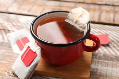 Tea bags and cup of aromatic drink on wooden rustic table, closeup